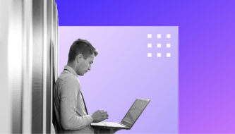 Mann mit Laptop in der Hand lehnt an Server-Regal mit lila Hintergrund.